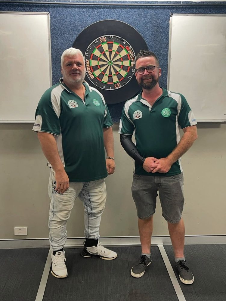 The in-house doubles winners in front of a dartboard